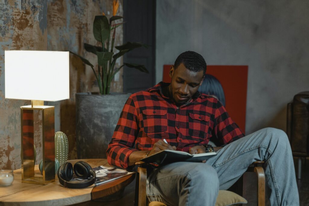 A man writing goals in a journal while sitting at a desk, illustrating unstoppable faith and determination to stay focused despite distractions.