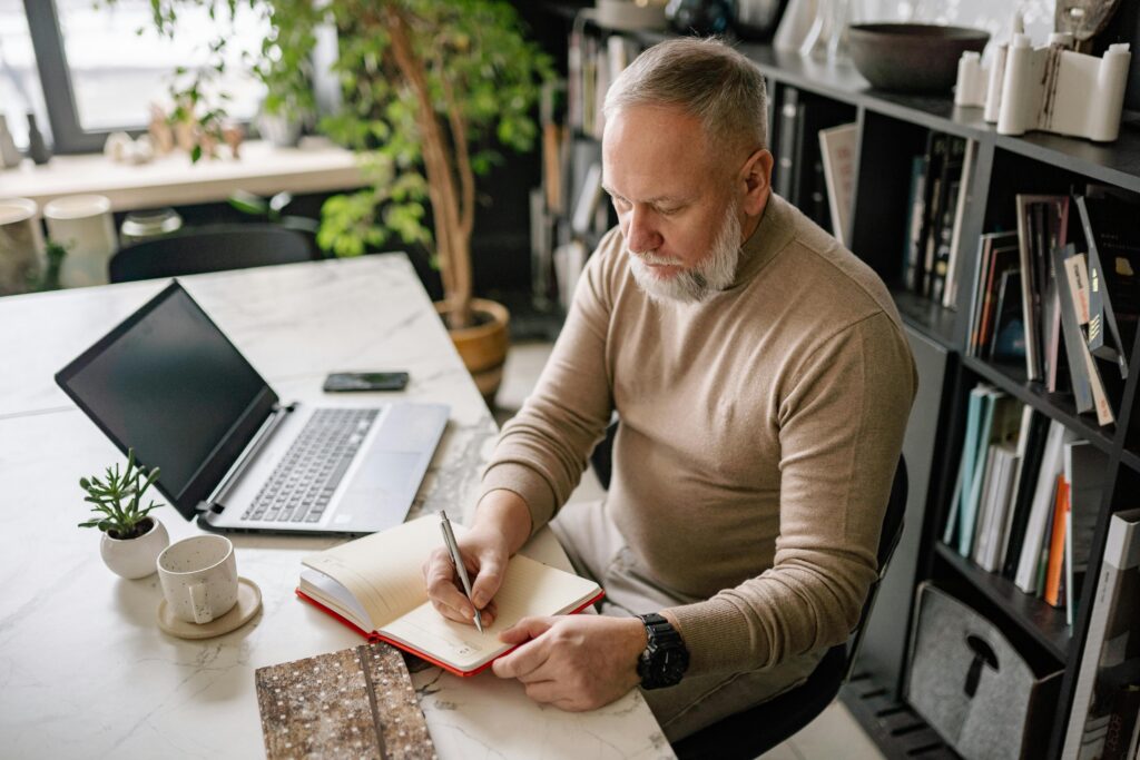 Closeup of a man writing goals in a journal to define his mission and claim his unshakable destiny.