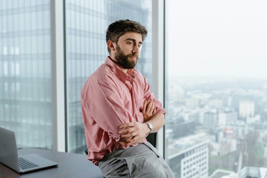 A man in deep thought looking out a window, symbolizing resilience and reflection after setbacks in life.