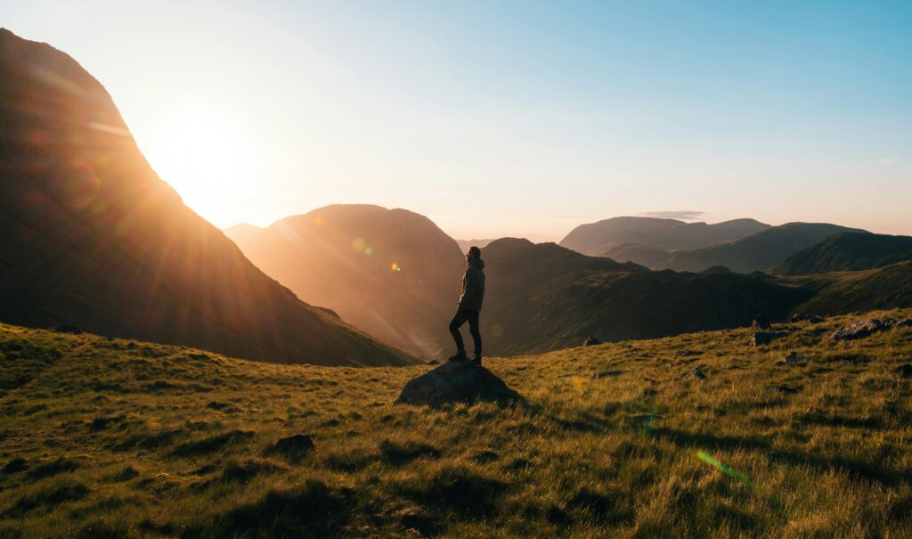 A man standing at sunrise on a mountain peak, symbolizing a men over 35 life overhaul and new beginnings