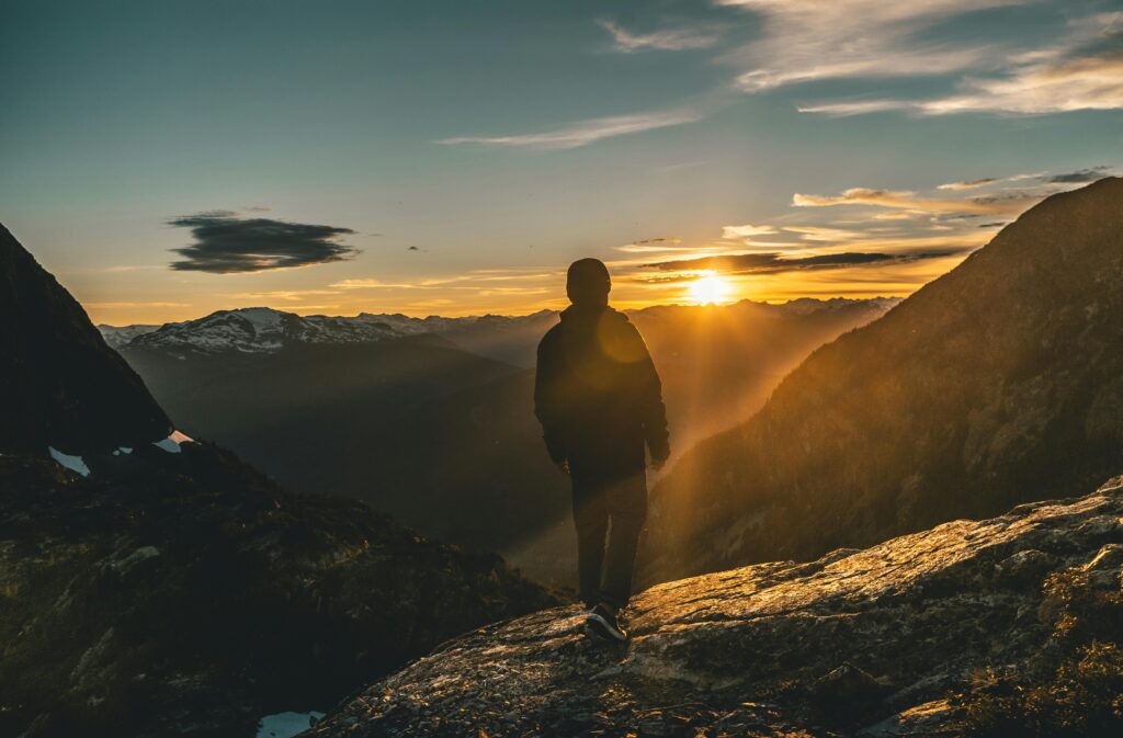 Man on mountain peak visualizing his unstoppable vision at sunrise