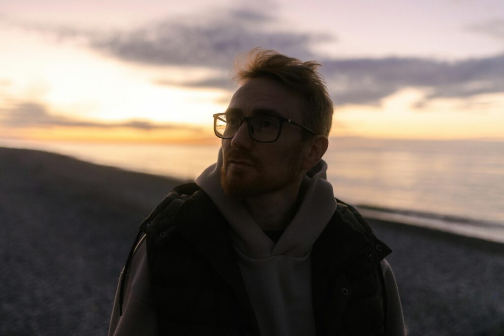 A man in midlife stands contemplatively at sunset, symbolizing introspection and life overhaul.